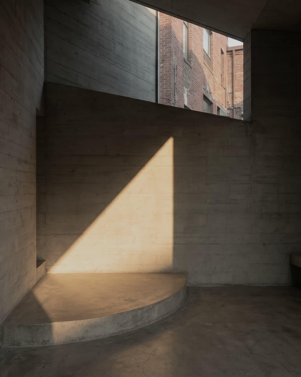 A quiet concrete interior with a precise triangular plane of daylight